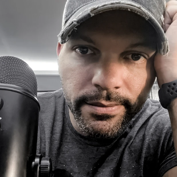 George sitting at his desk with a Yeti microphone in the foreground