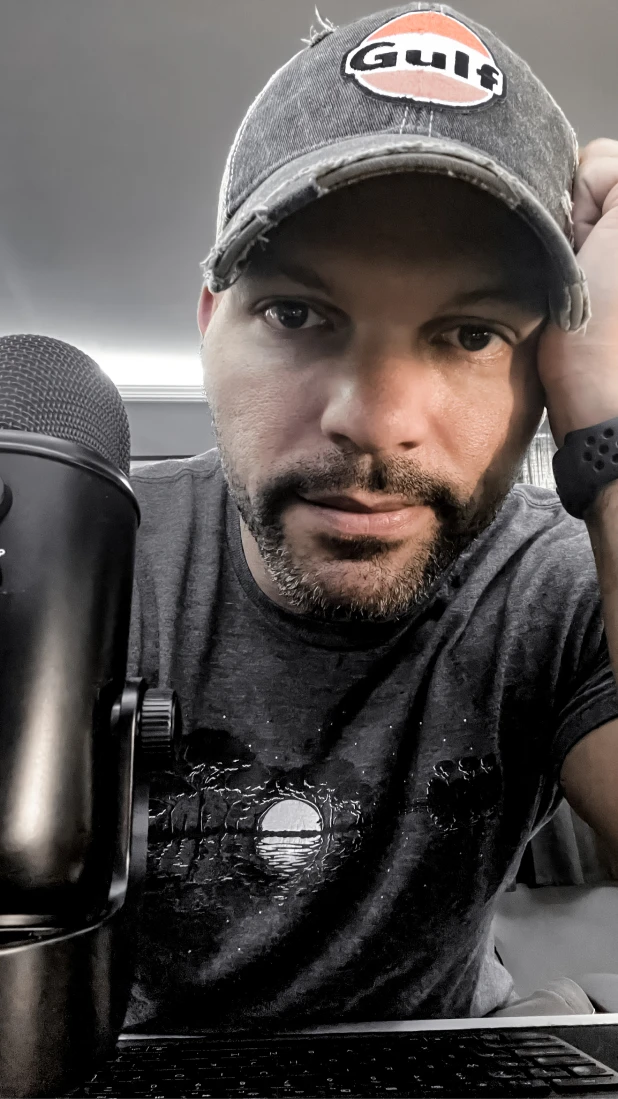 George sitting at his desk with a Yeti microphone in the foreground