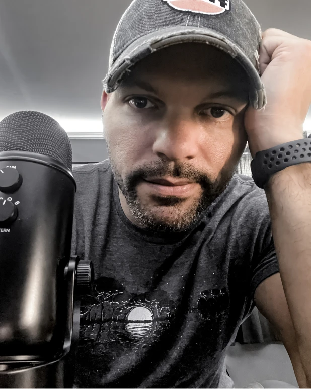 George sitting at his desk with a Yeti microphone in the foreground